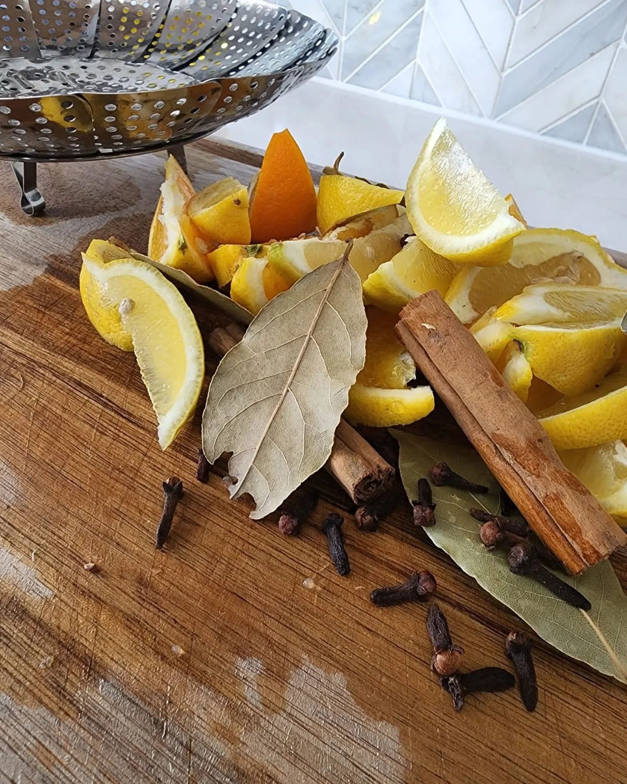 Lemon, cinnamon, bay leaf, and cloves beside steamer basket for placenta steam preparation